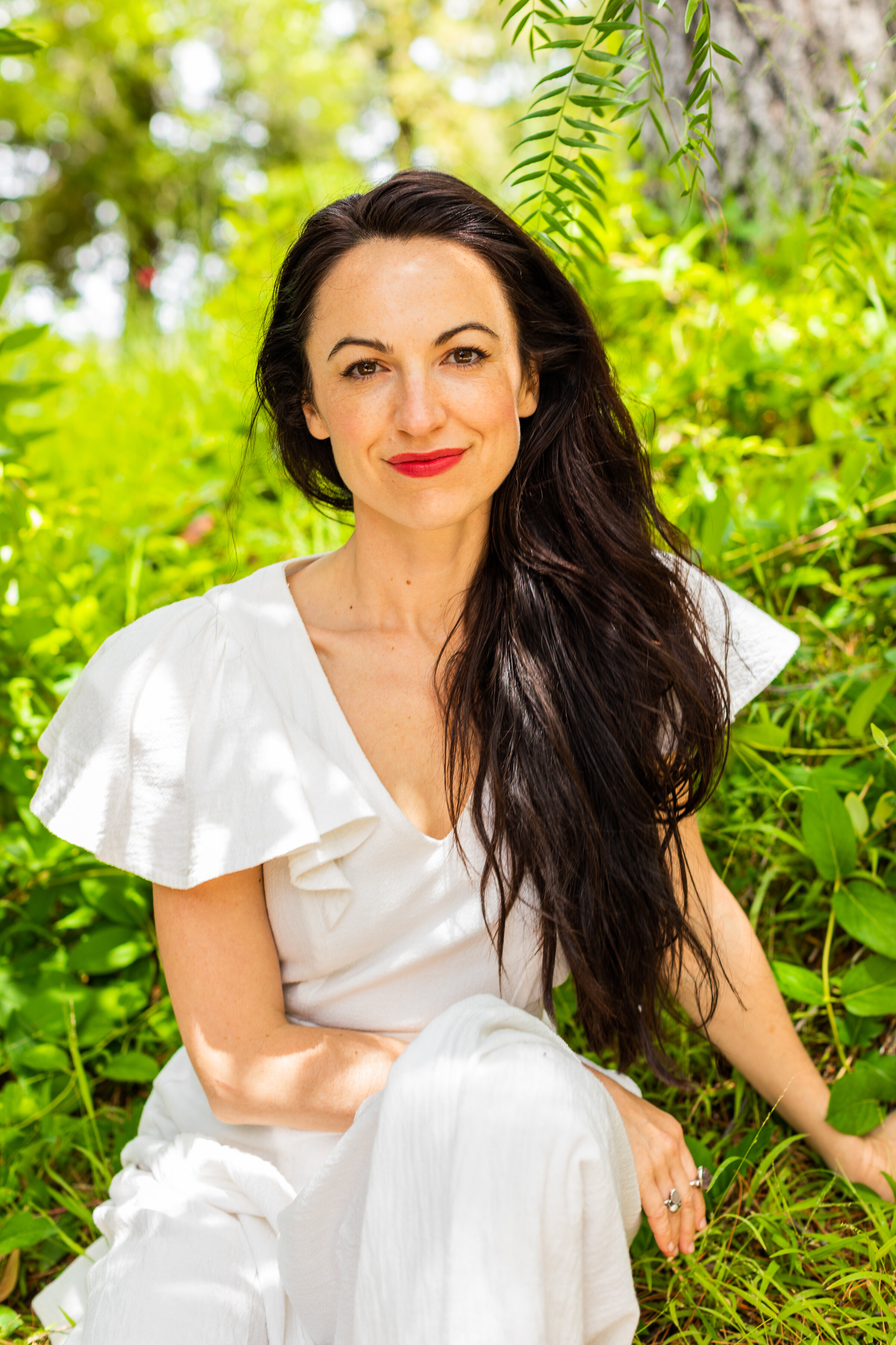 Alexandra Hulme seated in the grass in a white dress